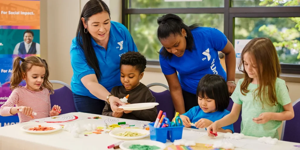 YMCA staff working with children to create arts and crafts