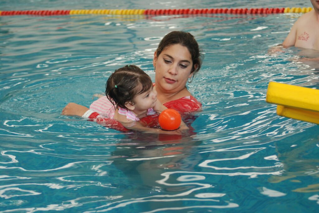 An adult assisting a child in a swimming pool
